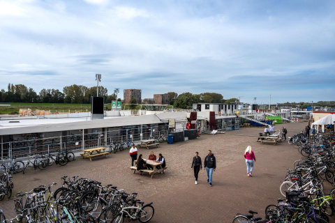 Schip voor asielopvang aan kade met picknicktafel, fietsenrekken en bewoners