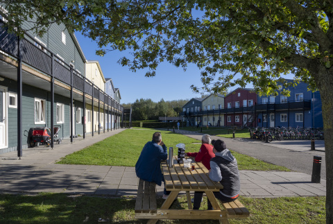 3 bewoners aan een picknicktafel op binnenplaats van opvanglocatie