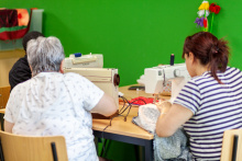Vrouw met witte blouse en vrouw met zwartwit gestreept shirt werken achter de naaimachine