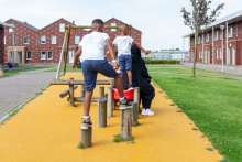 Twee kinderen spelen in Ter Apel in het speeltuintje terwijl hun moeder zit te wachten