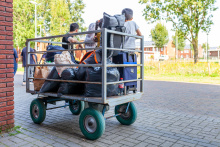 Asielzoekerfamilie wacht met kar vol bagage op vervoer van Ter Apel naar een volgende locatie